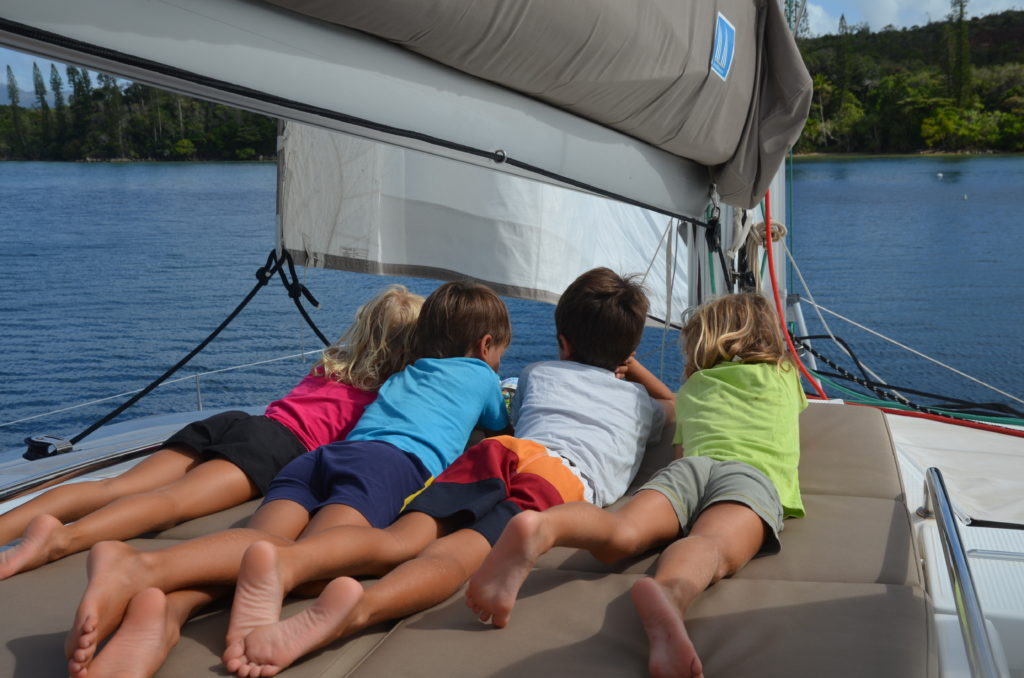 Enfants sur le sundeck du catamaran abaca regardant le lagon et ses ilots